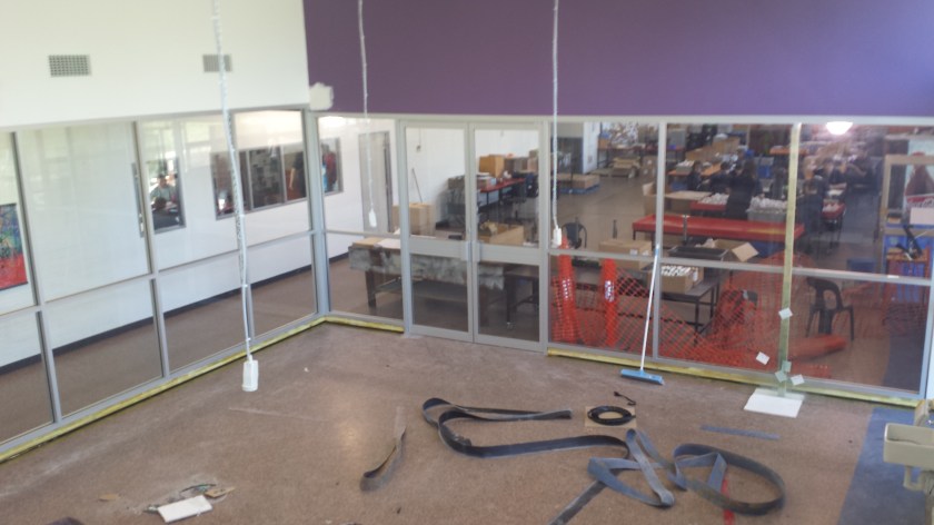 Office partition with pivot doors and clear laminate glass.