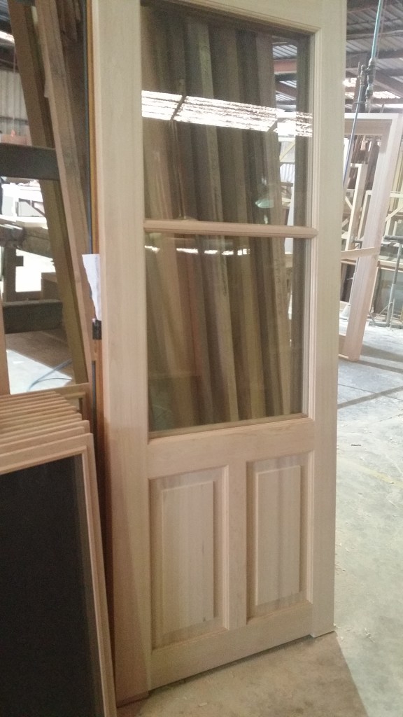 Cedar door, with clear laminate glass and recessed timber panels. 1 of a pair.